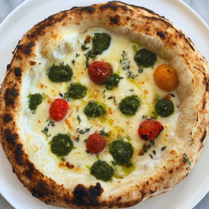 Heirloom tomatoes and pesto dollops on a white four cheese pizza